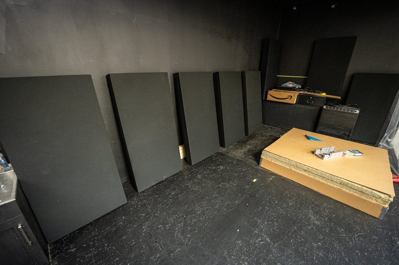 A row of finished and in-progress Studio 12 acoustic panels standing against a wall, alongside raw stone-wool core material